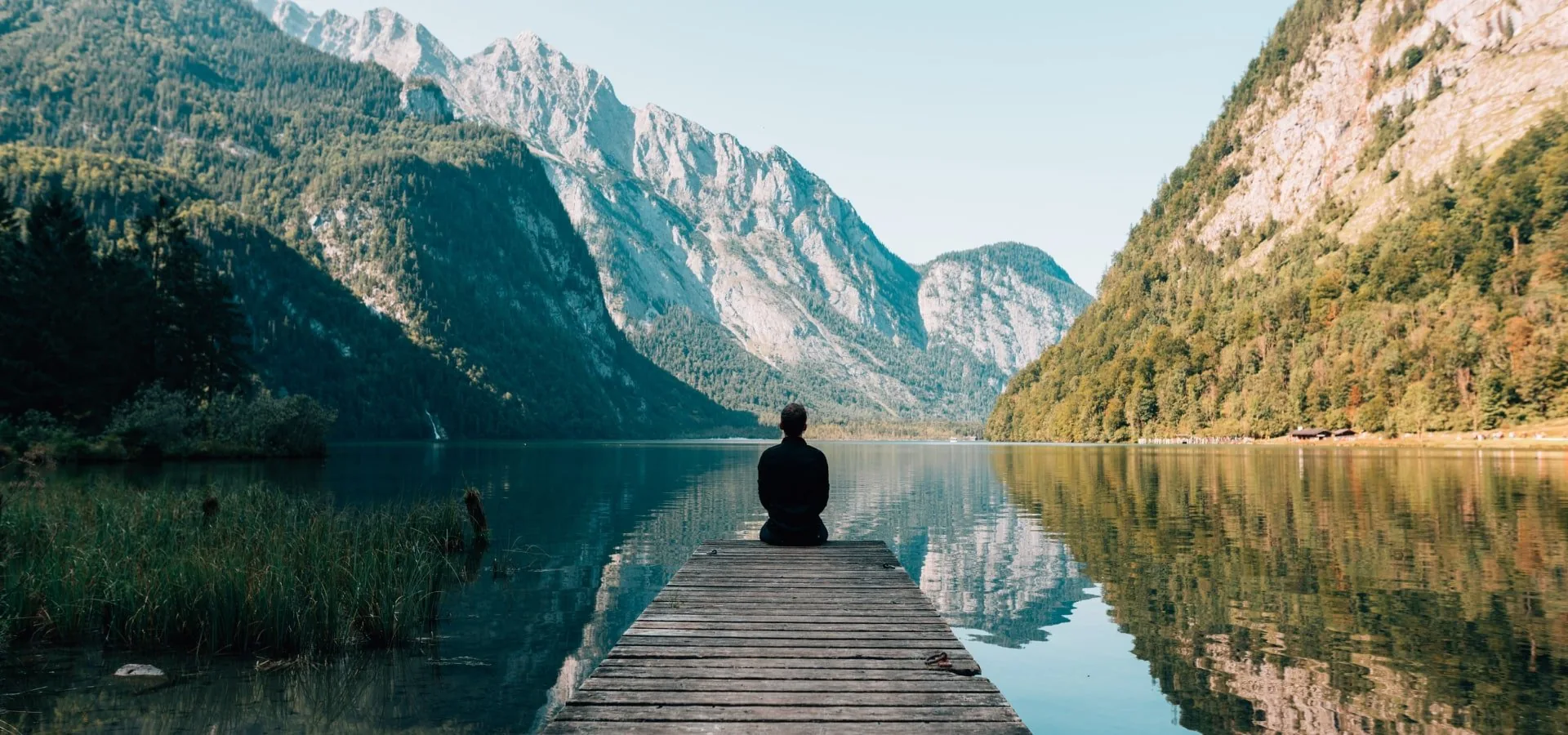A traveller on a jetty in a mountain fjord